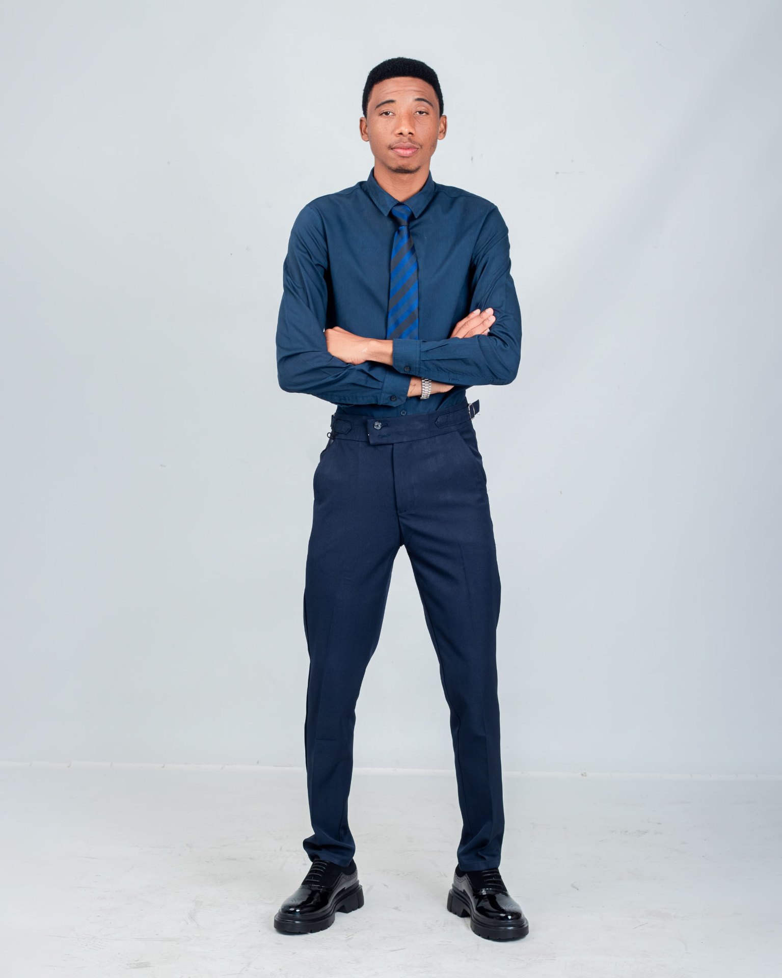 Man in navy formalwear standing with his arms crossed