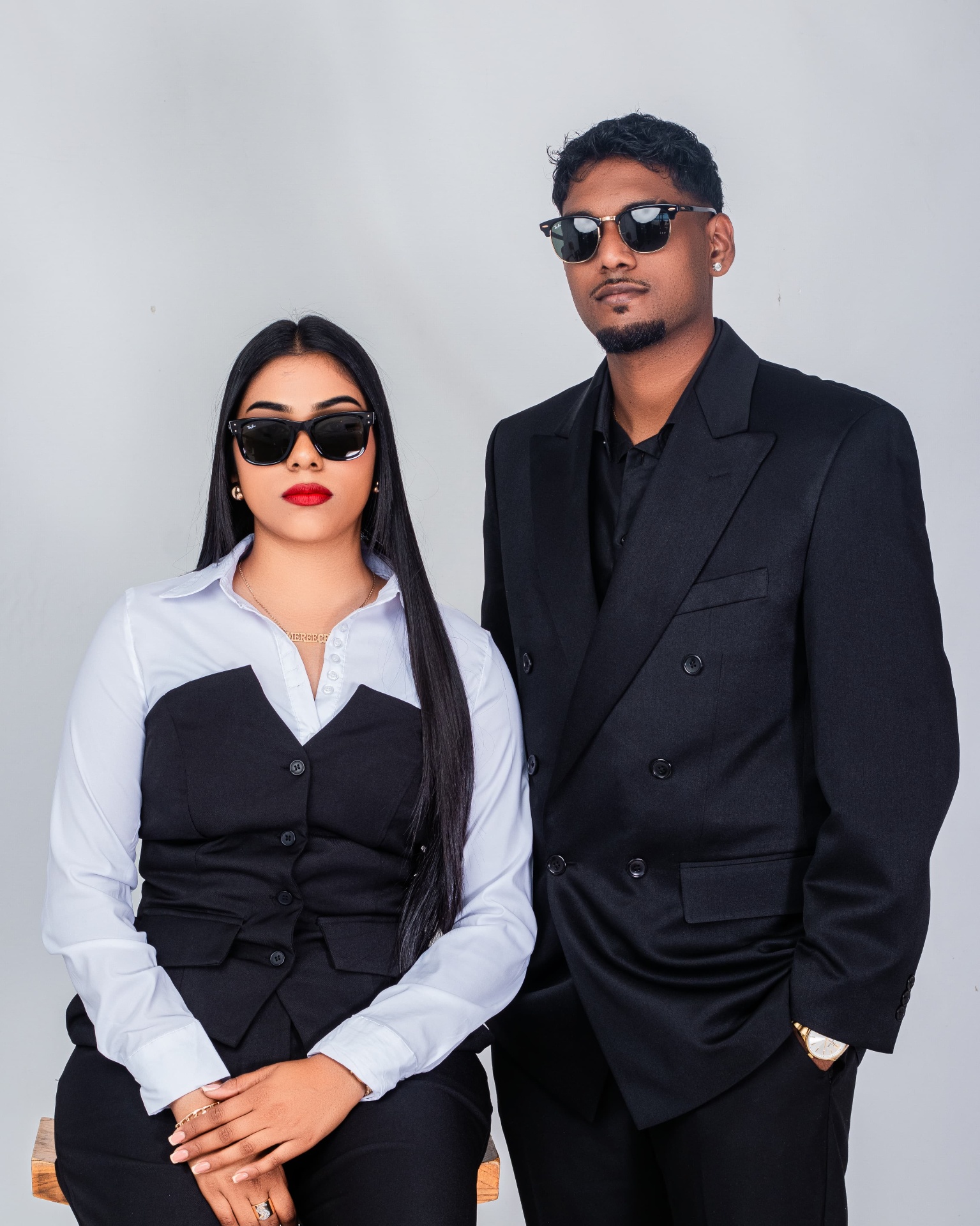 Couple in matching black formalwear and sunglasses