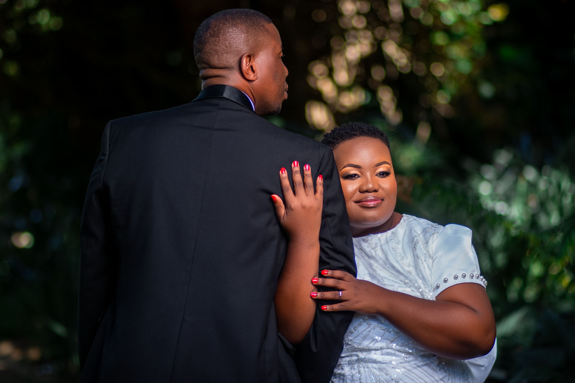 Bride resting on her partner's shoulder outdoors
