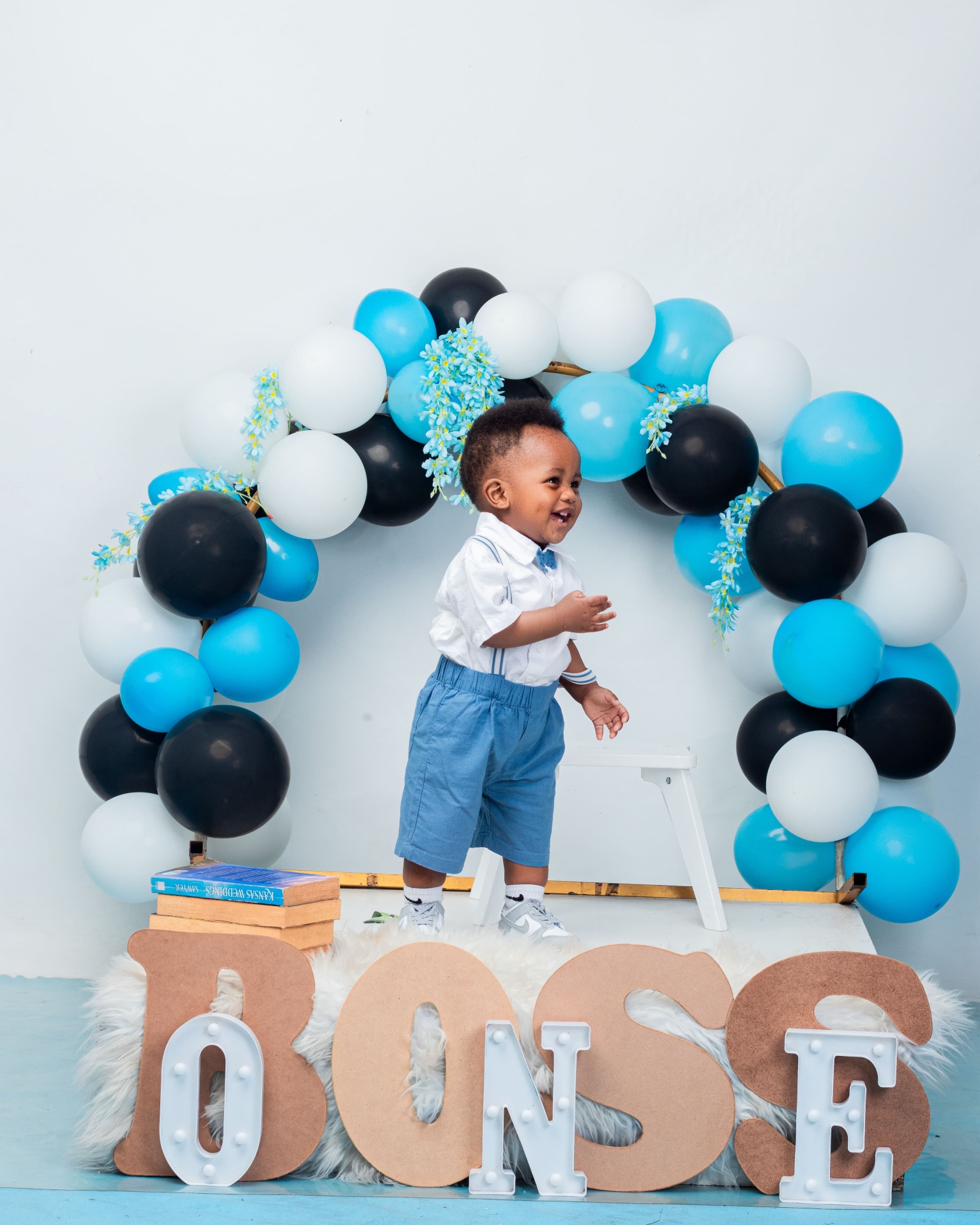Toddler boy at a blue balloon arch with BOSS letters