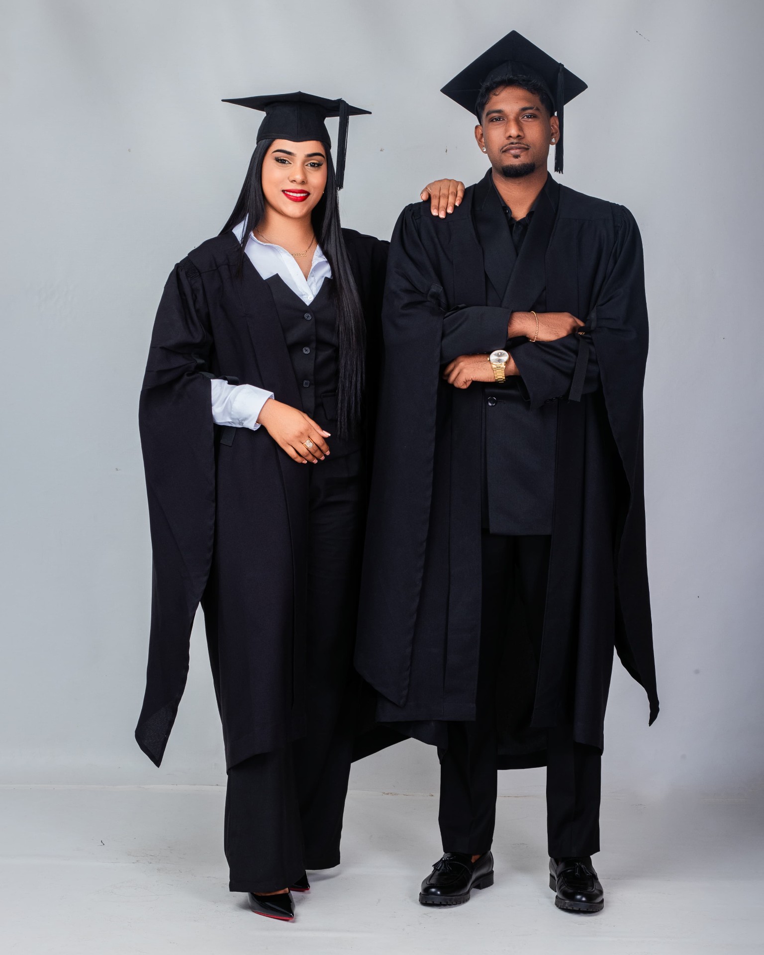 Two graduates in gowns photographed in studio