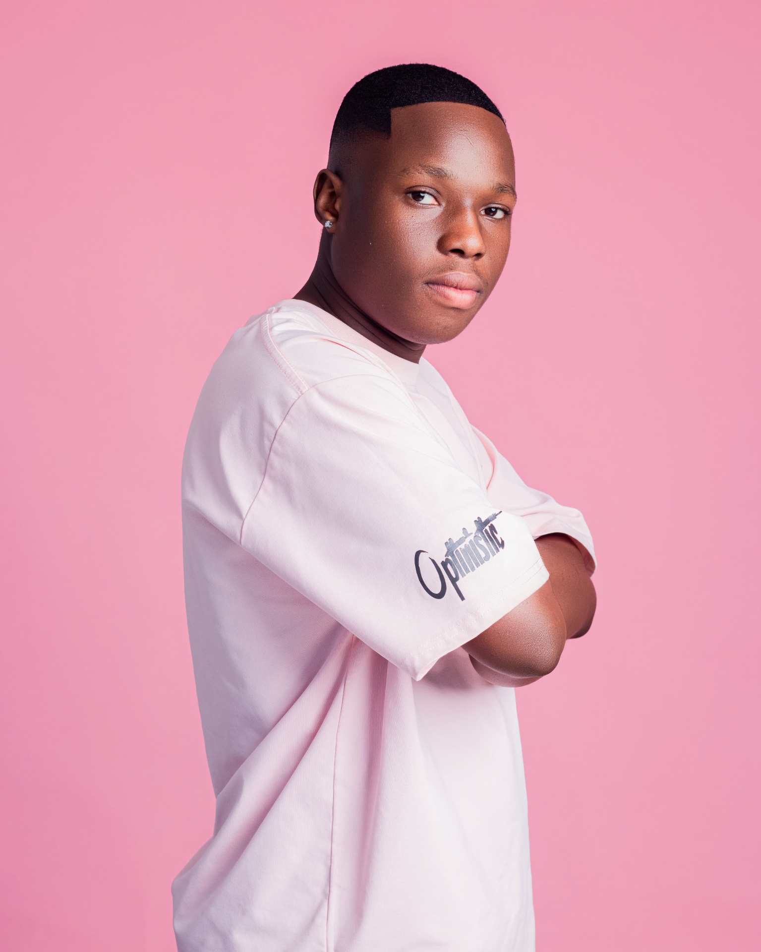 Studio portrait of a man in a pale pink T-shirt with folded arms