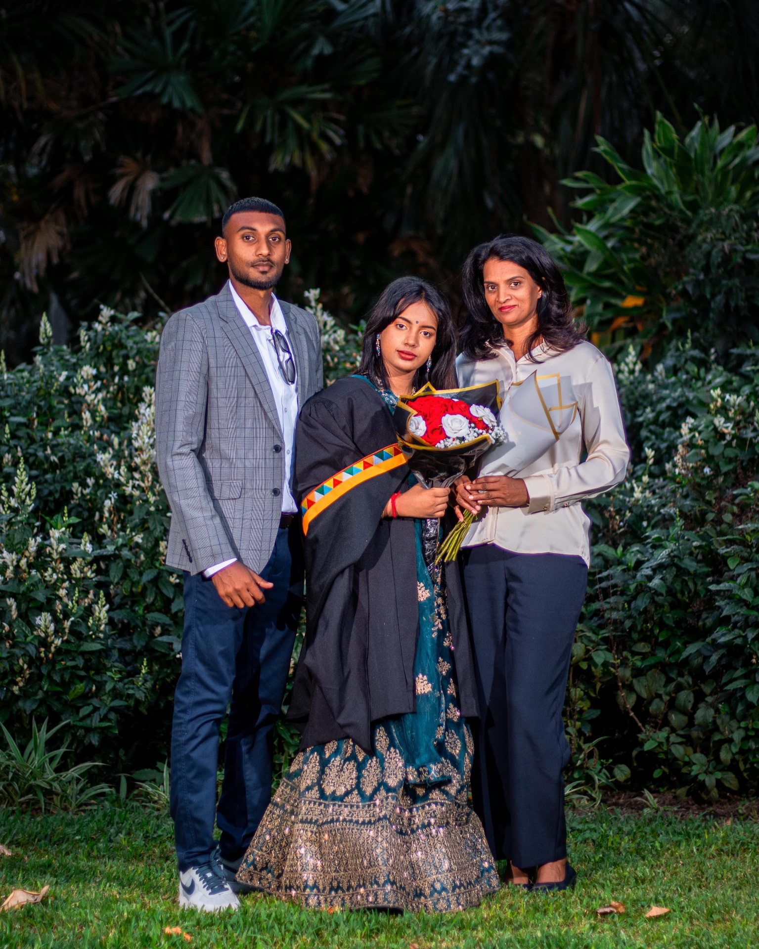 Graduate with parents holding roses in a garden
