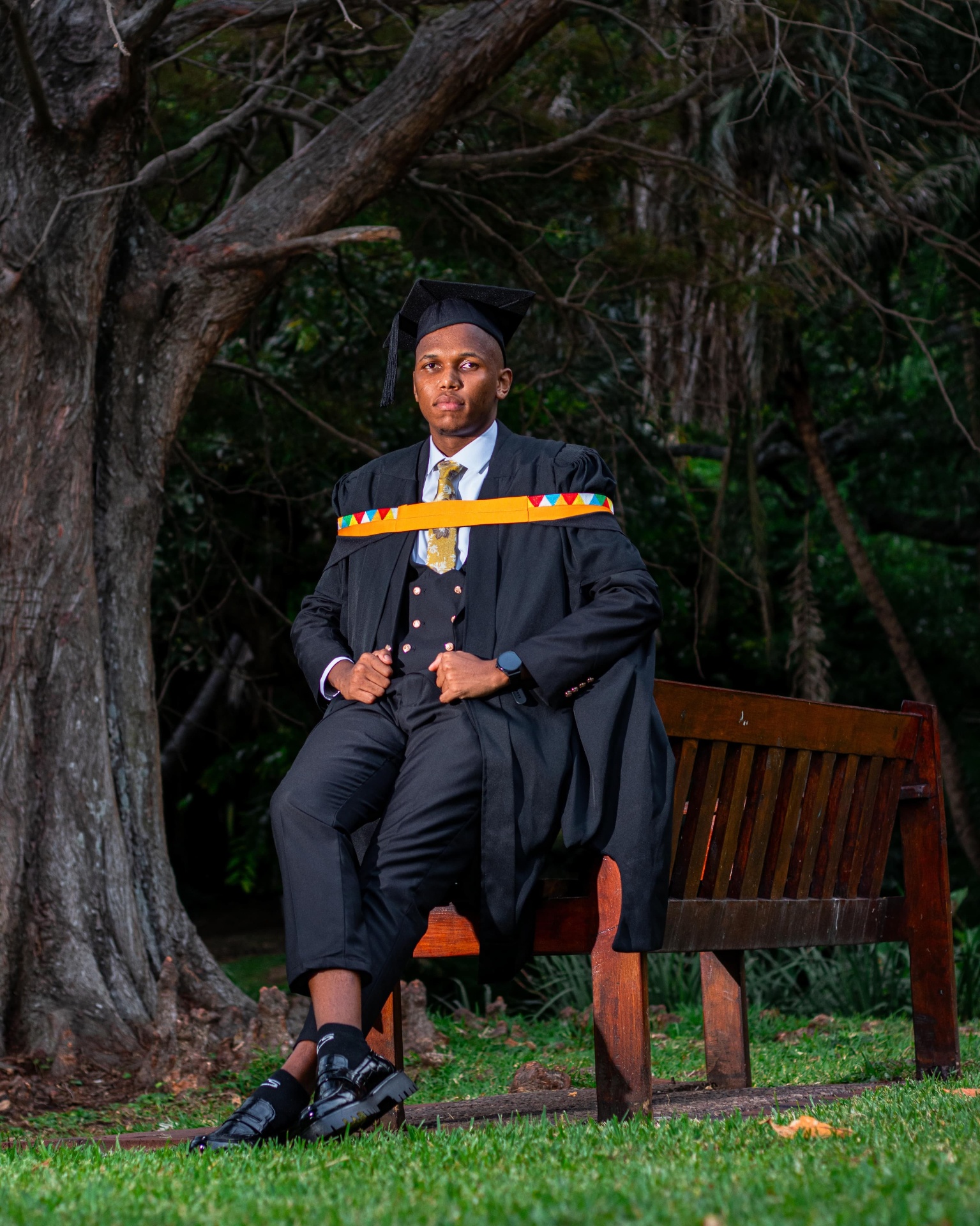 Graduate seated on a bench in a garden setting