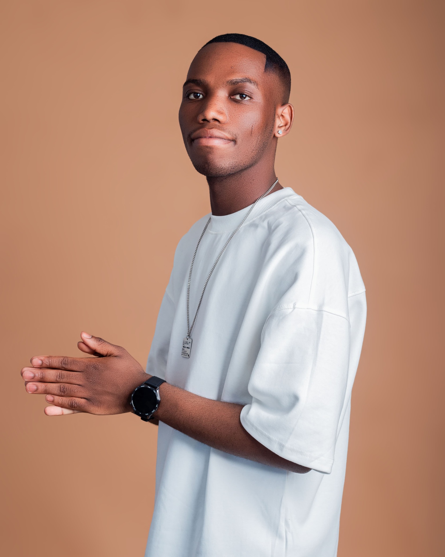 Man in a white T-shirt standing against a warm backdrop