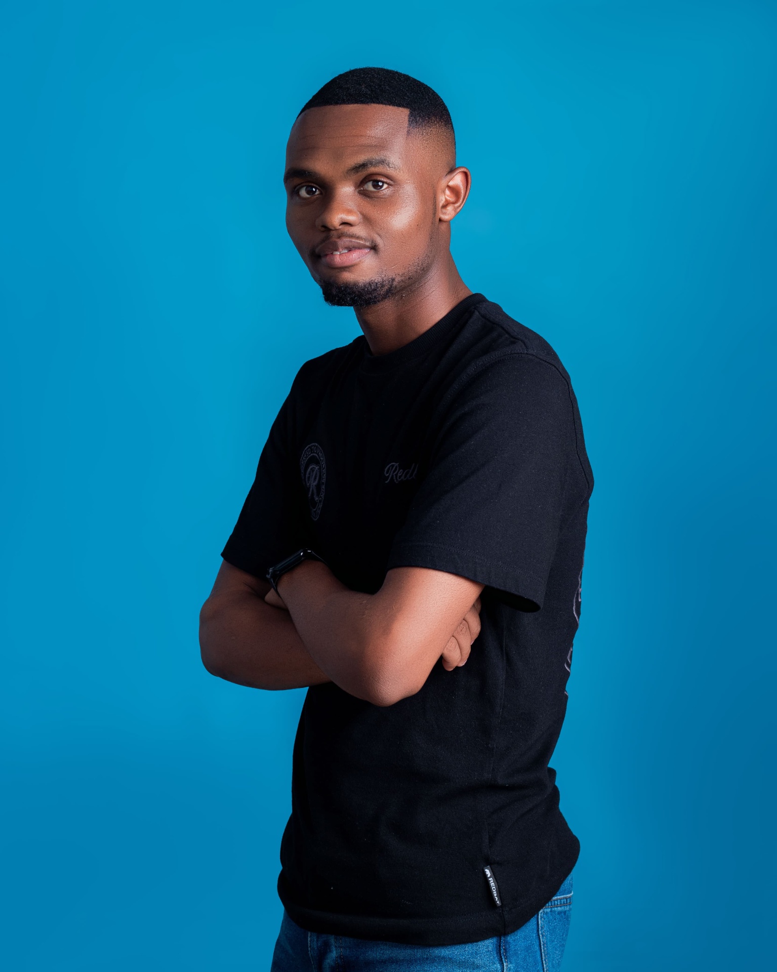Studio portrait of a man in a black T-shirt with folded arms