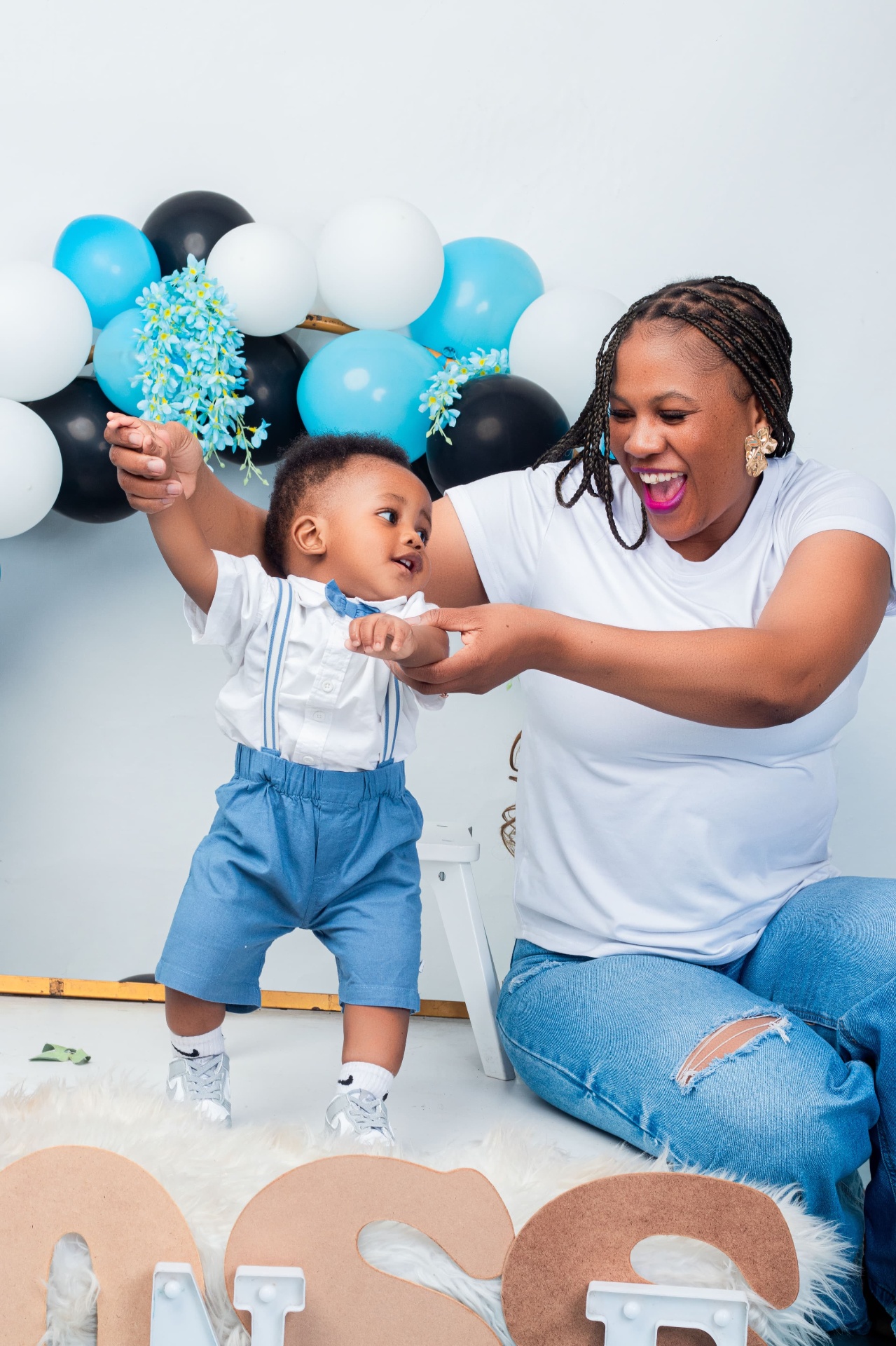 Mother dancing with her young son at a blue balloon birthday set
