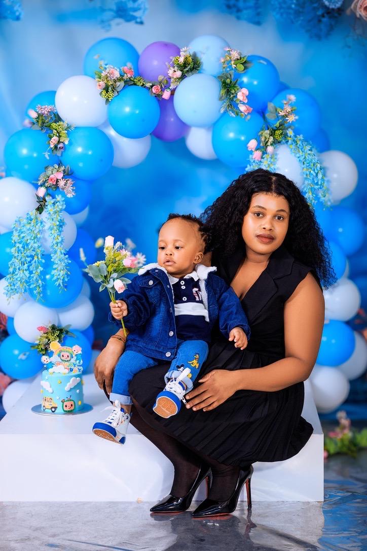 Mother and her baby boy with flowers at a blue balloon birthday set