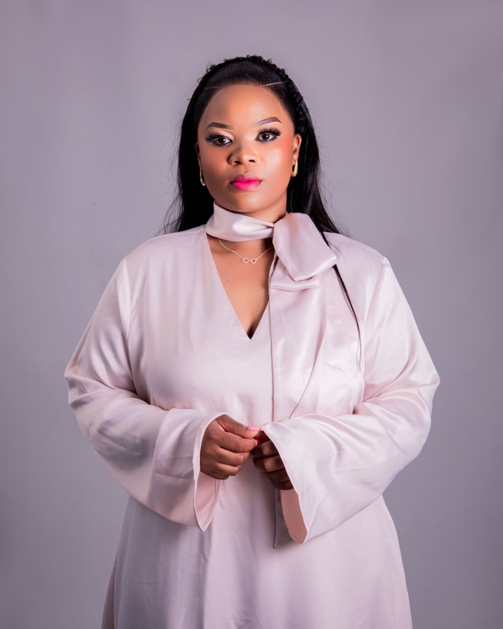 Studio headshot of a woman in a blush satin dress
