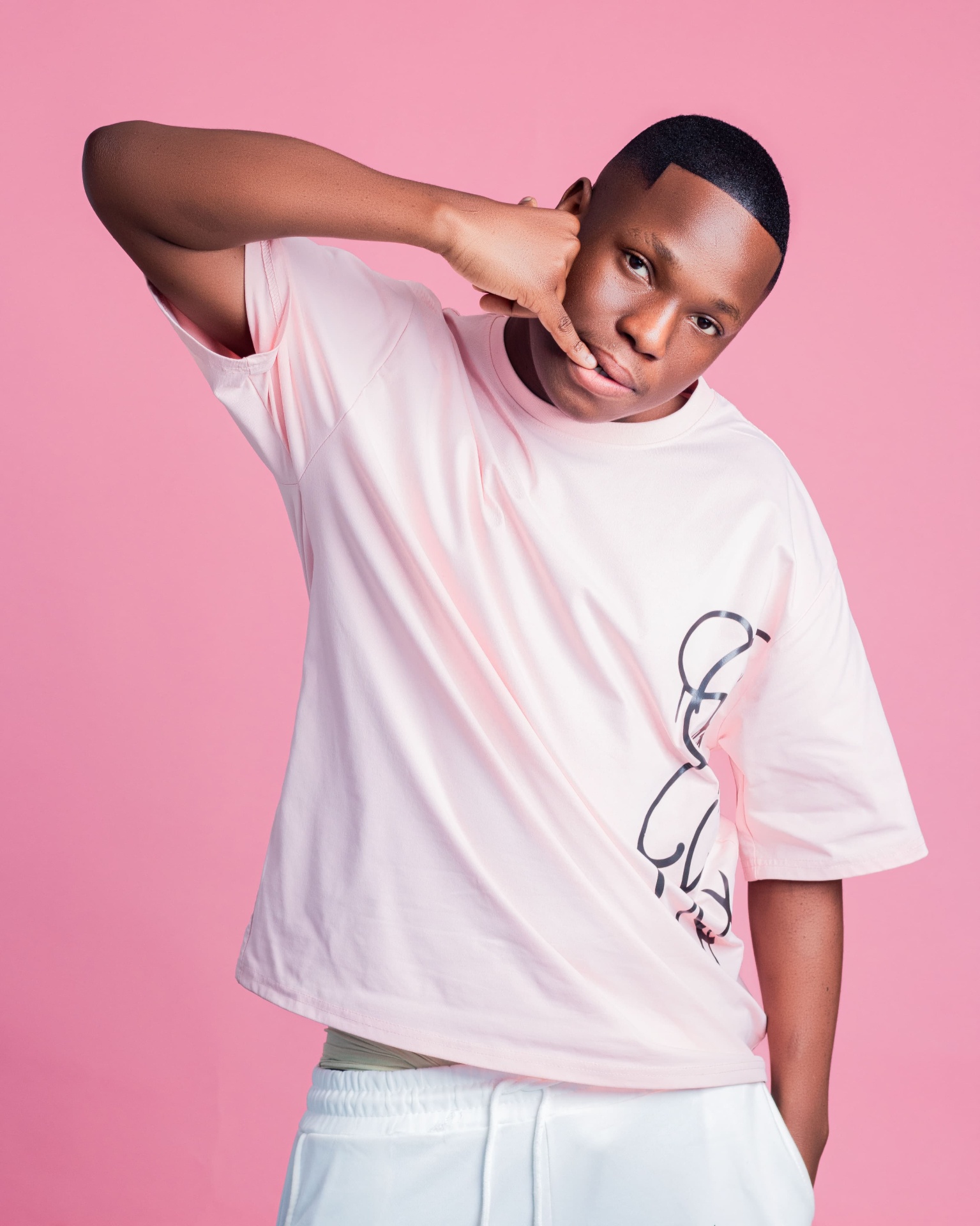 Man in a pale pink T-shirt making a phone gesture
