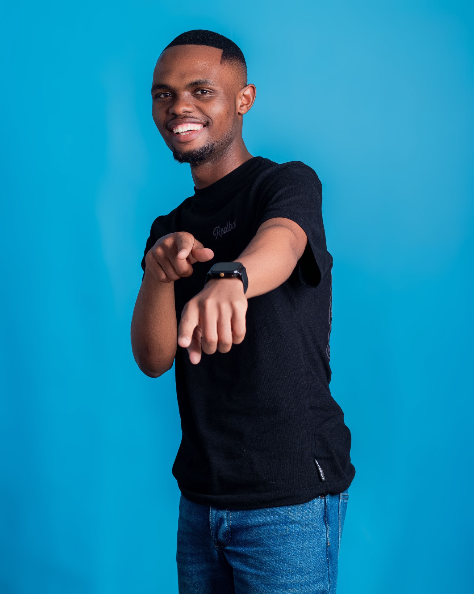 Man in a black T-shirt pointing toward the camera