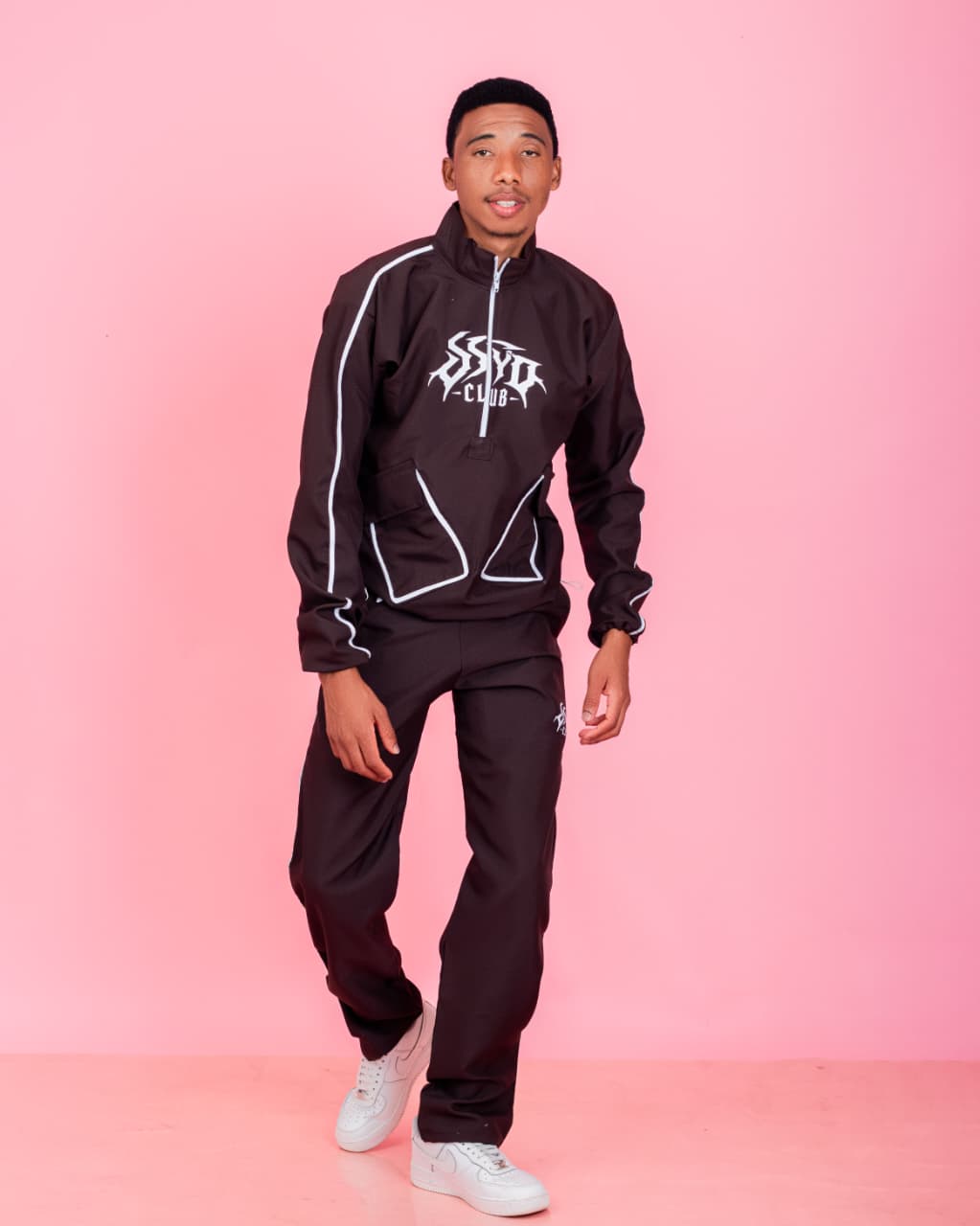 Full-length studio portrait of a man in a black tracksuit