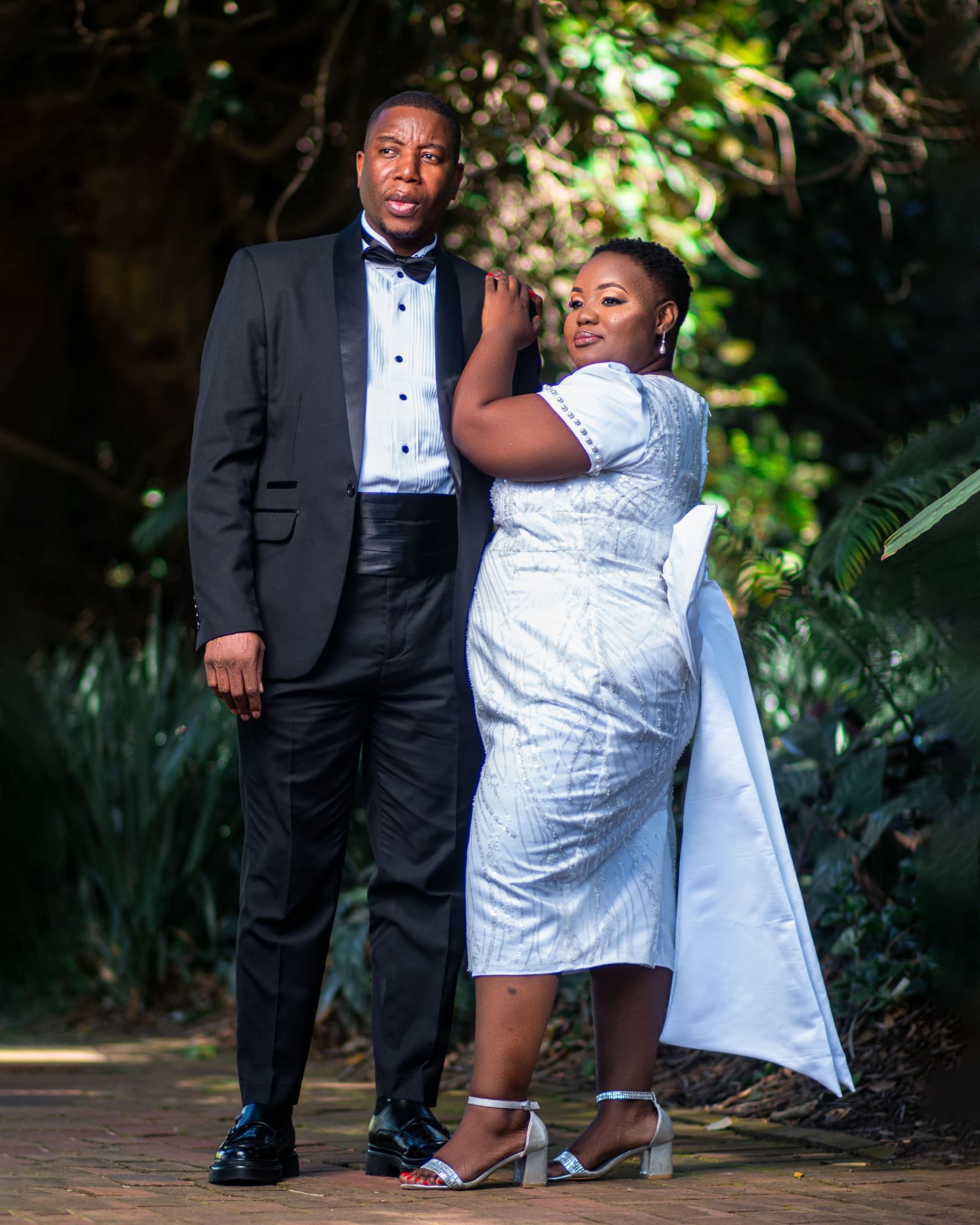 Couple in tuxedo and white beaded dress in a garden