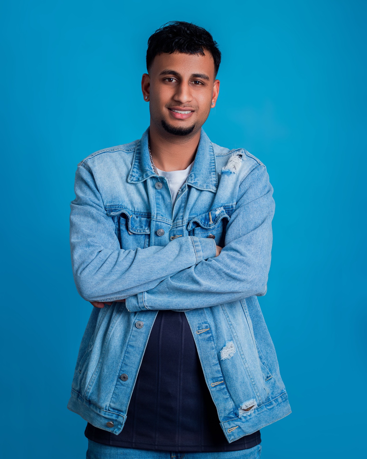 Man in a denim jacket standing with folded arms
