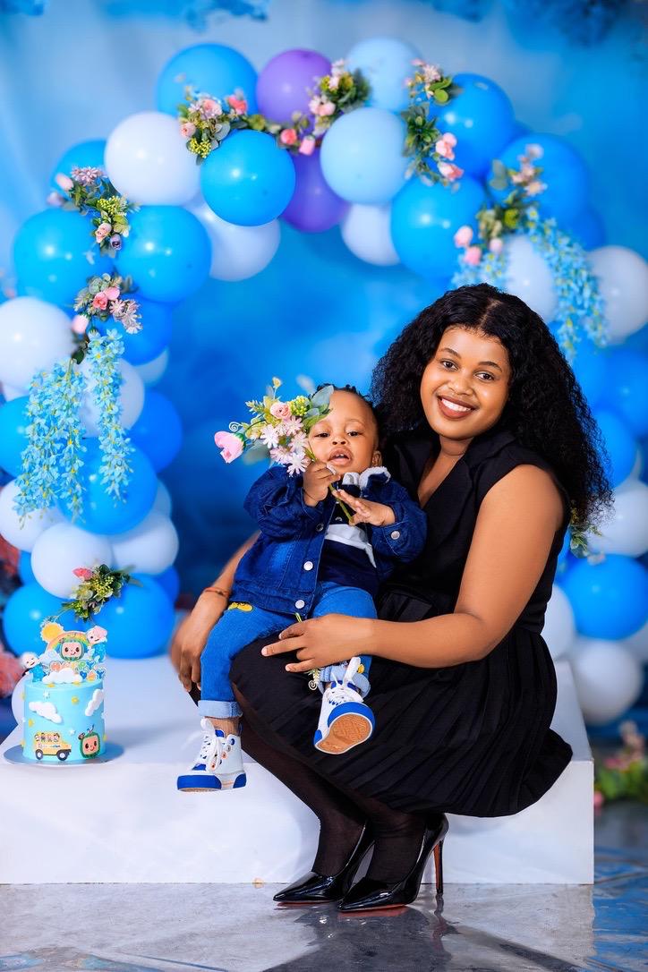 Mother holding her one-year-old son at a blue balloon arch