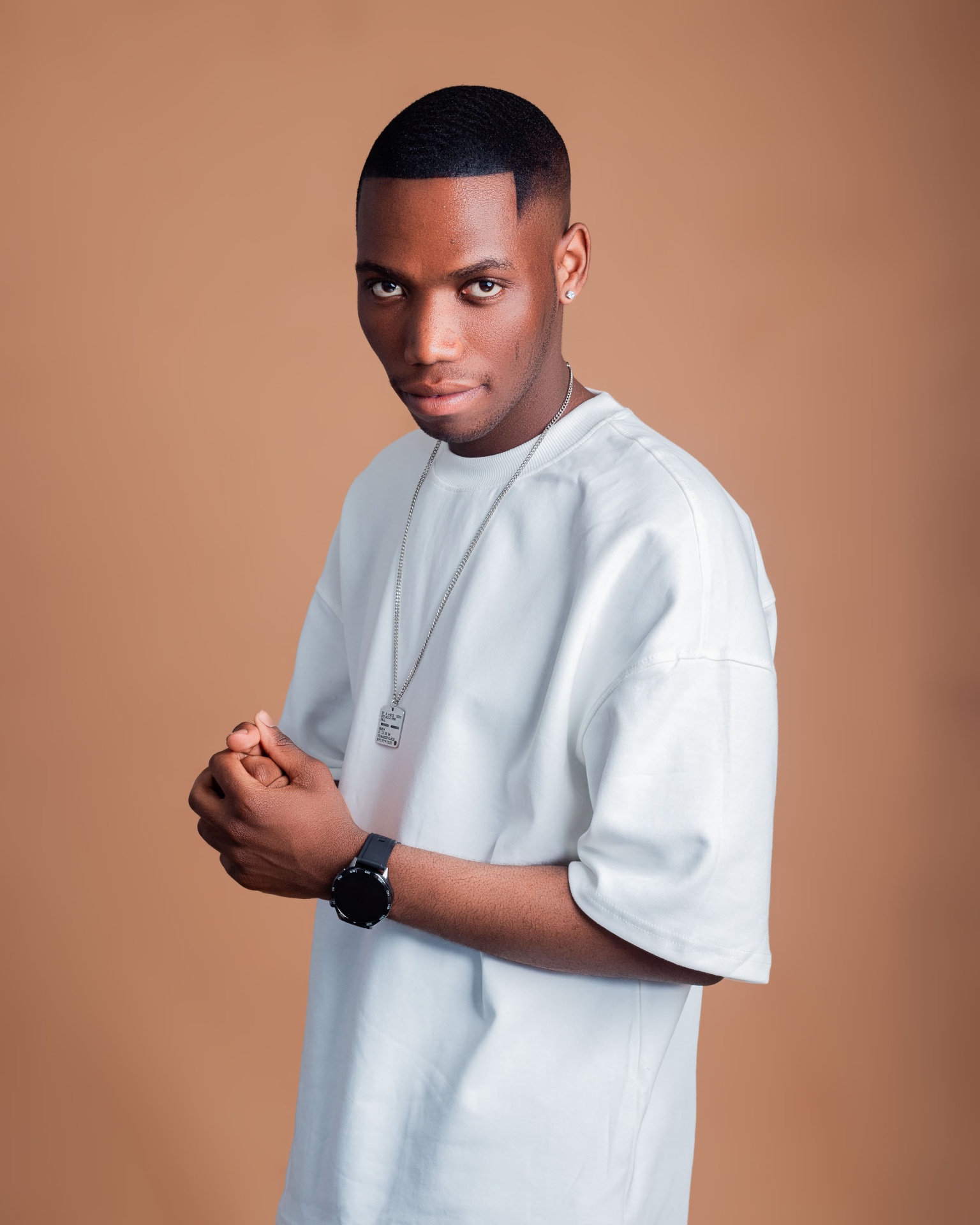 Man in a white T-shirt posing with clasped hands